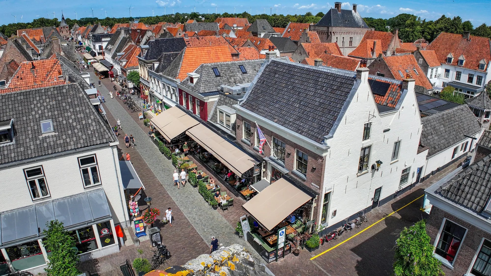 De Jufferenstraat in Elburg met het zonnige terras van De Haas en de Vischpoort aan het eind van de straat