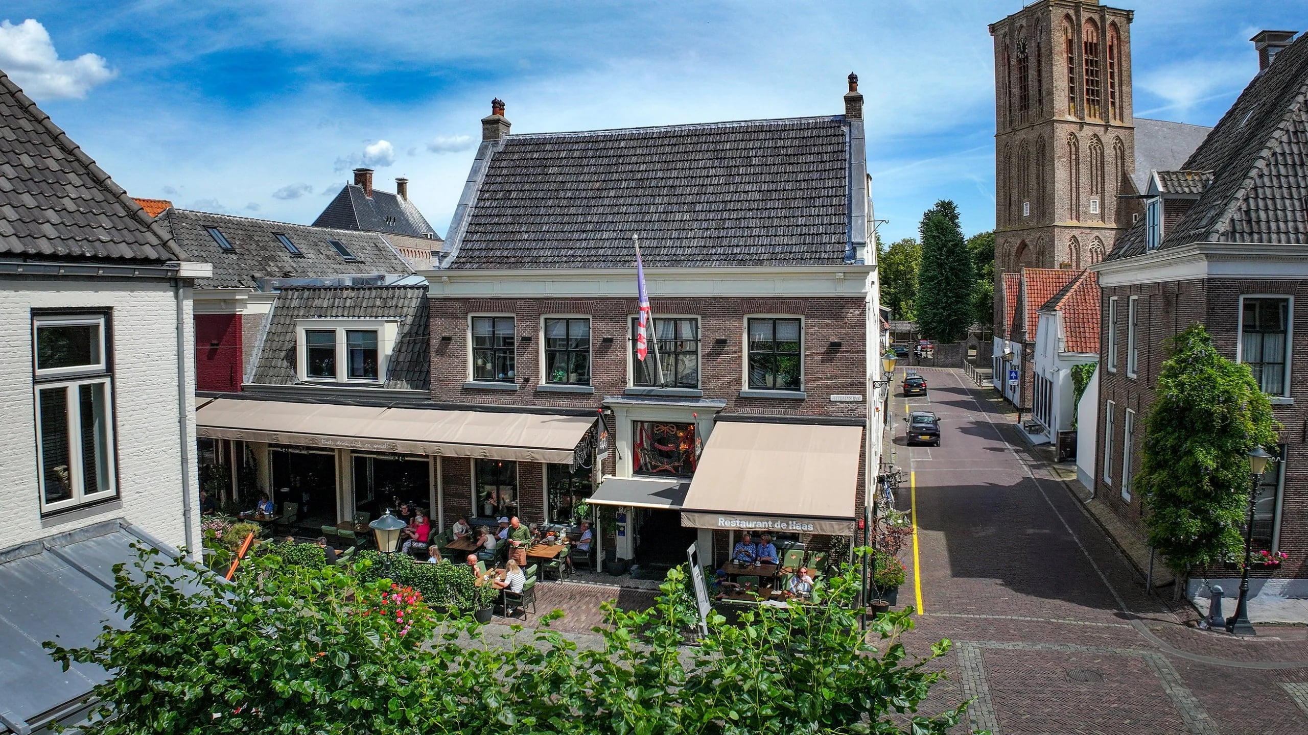 De Jufferenstraat in Elburg met het zonnige terras van De Haas en de Vischpoort aan het eind van de straat