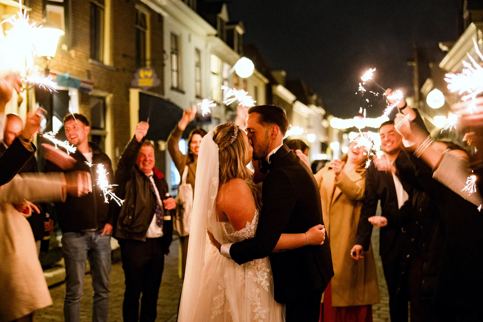 Bruidspaar kust elkaar tussen gasten met sterretjes op de avond van hun bruiloft bij De Haas Elburg