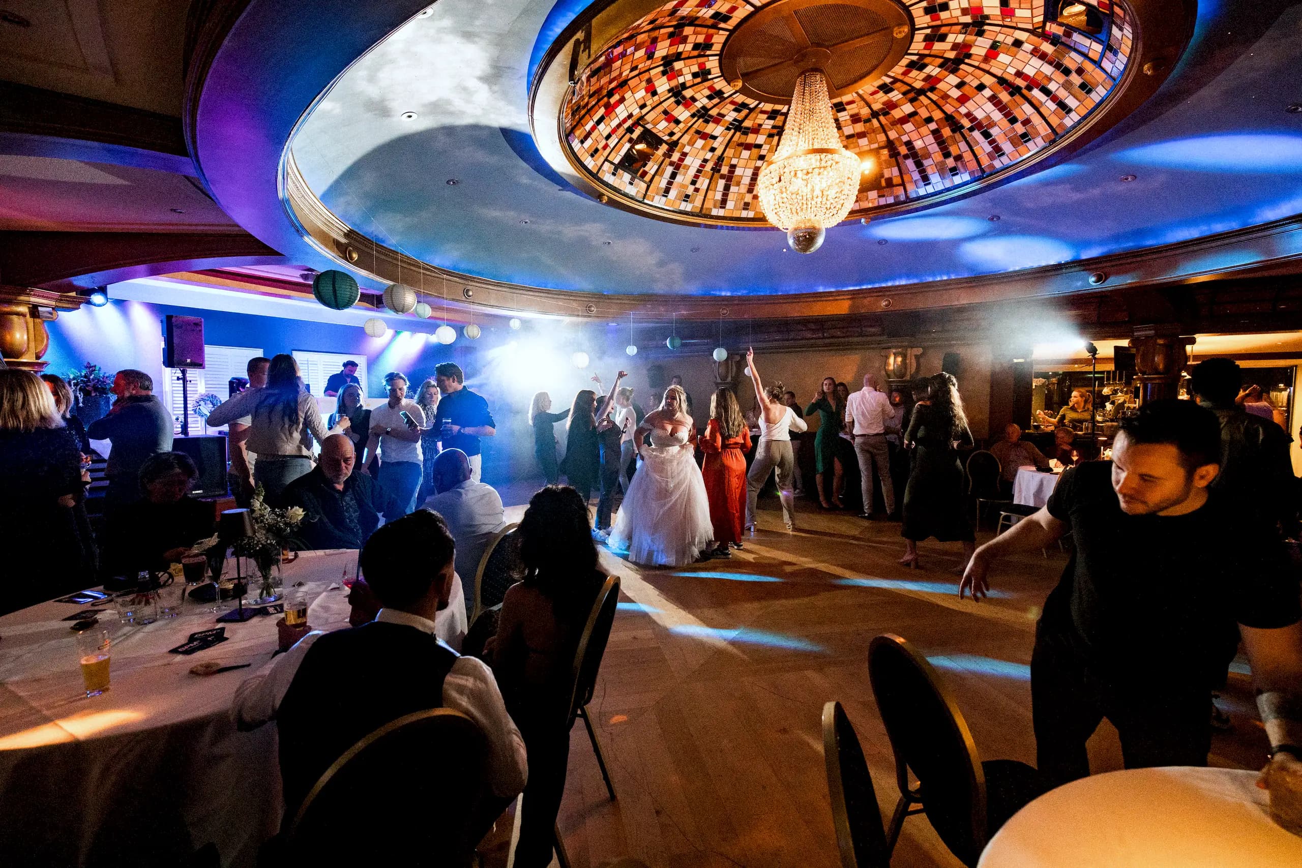 Bruid danst met haar gasten onder de glas-in-loodkoepel van de Sterrenzaal