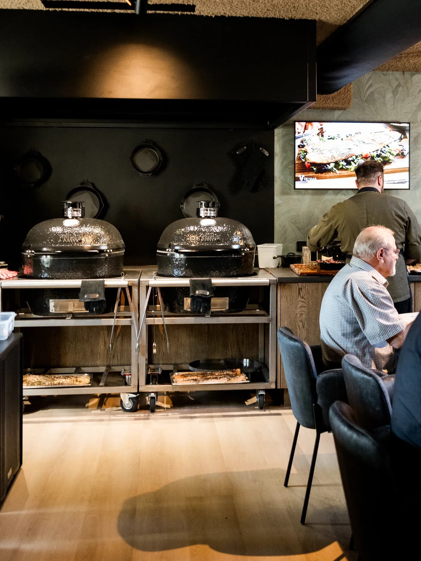 Twee kamado-grills in het restaurant van De Haas, met gasten aan tafel ernaast