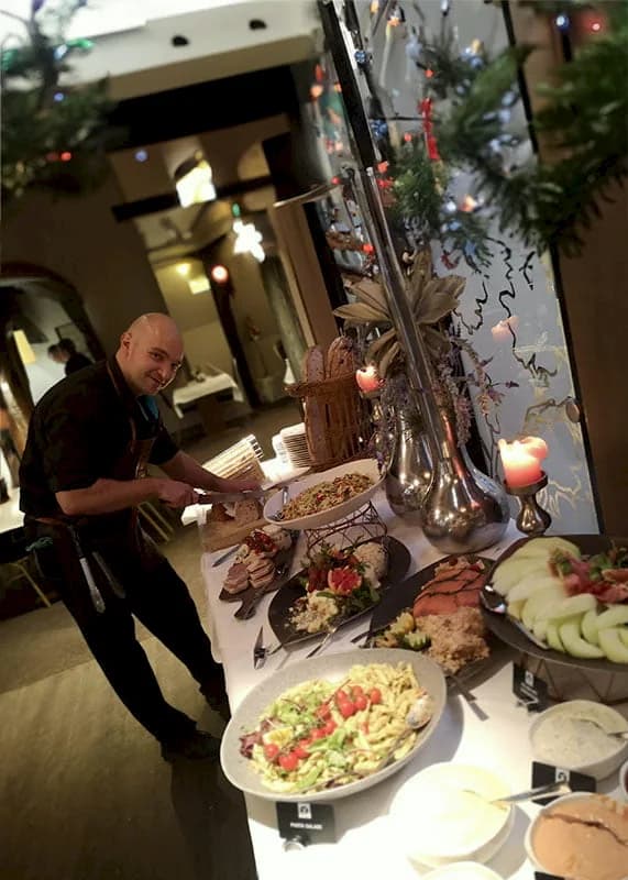 Medewerker van De Haas bij het koude kerstbuffet met salades, vleeswaren en kaarsen