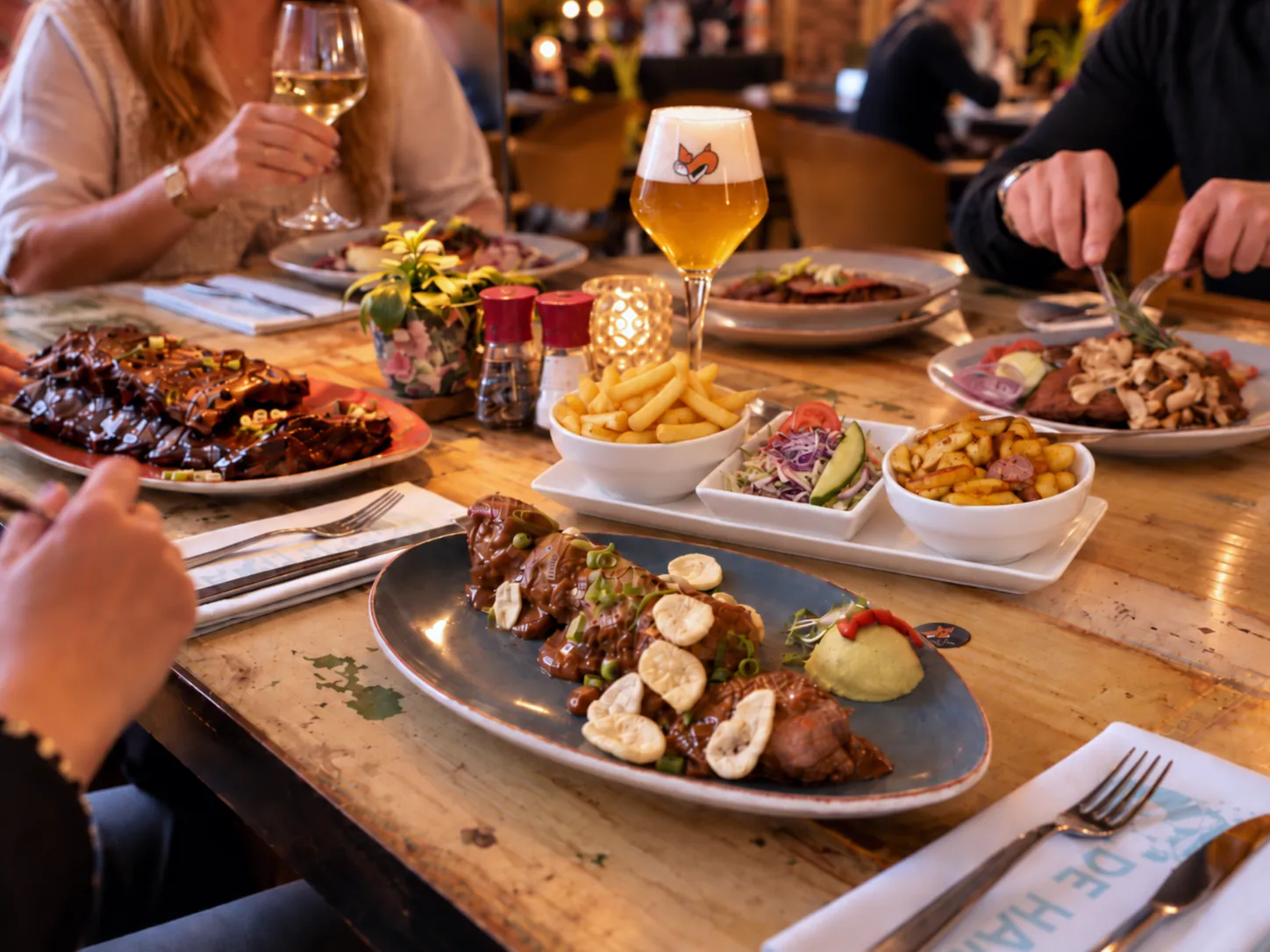 Volle tafel met spareribs, friet en een glas Vos-bier tijdens het diner bij De Haas Elburg
