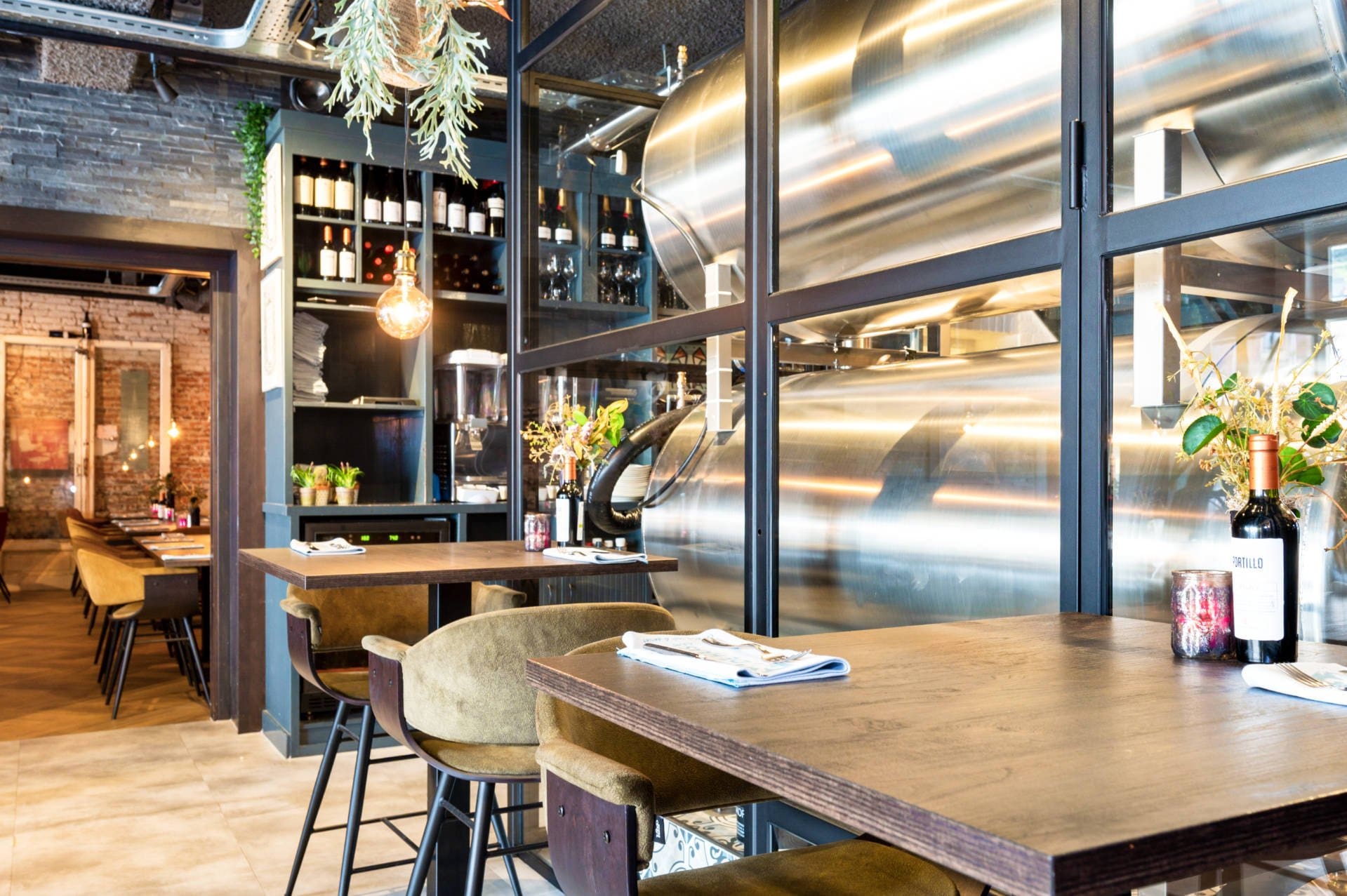 Het restaurant van De Haas met hoge houten tafels en rvs-tanks achter glas