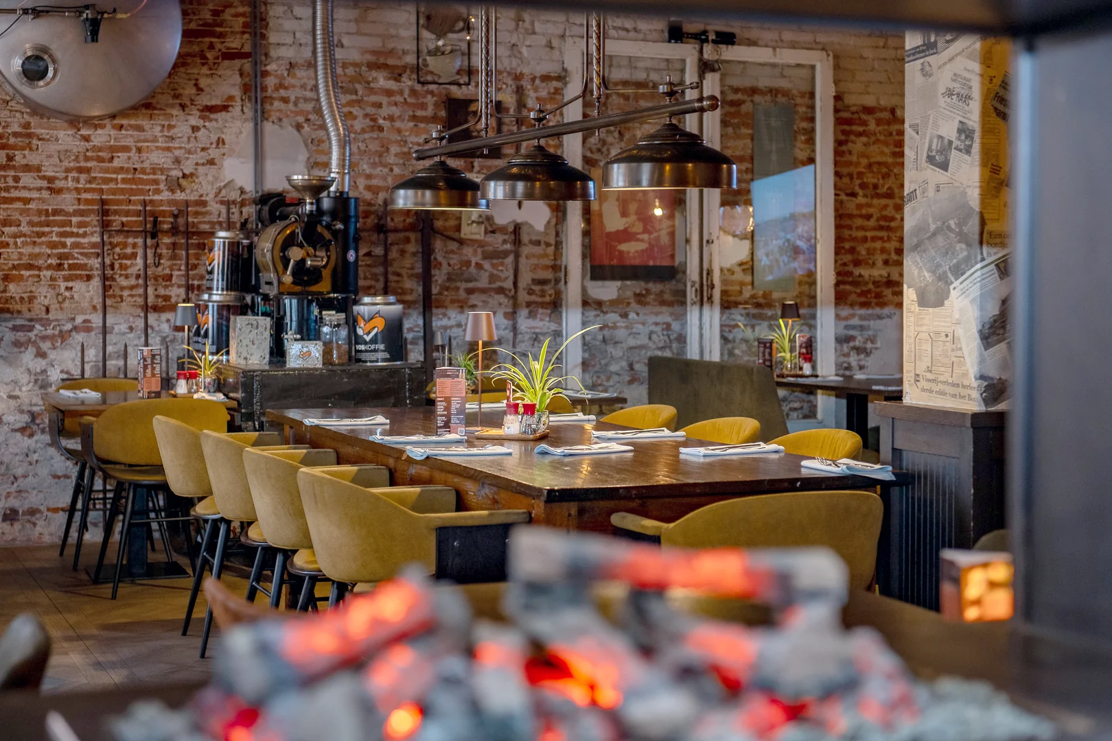 Lange gedekte houten tafel met okergele stoelen in het restaurant van De Haas