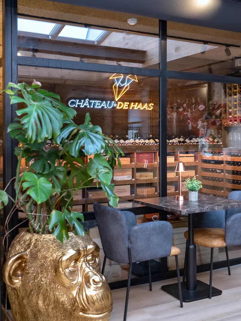Ingang van wijnkamer Chateau De Haas met lichtreclame en een tafel voor twee