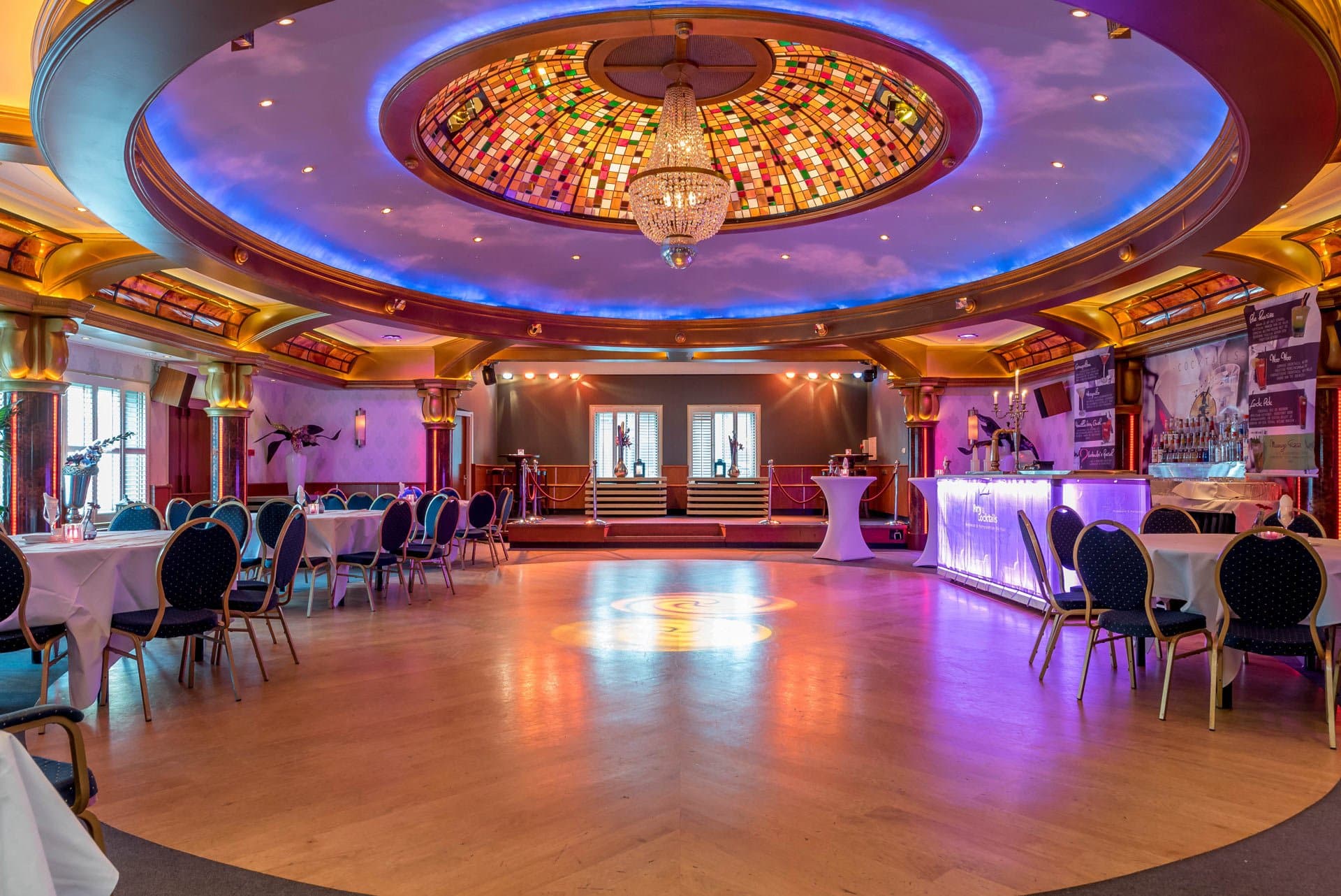 Sterrenzaal met glas-in-loodkoepel, kroonluchter, dansvloer en verlichte bar