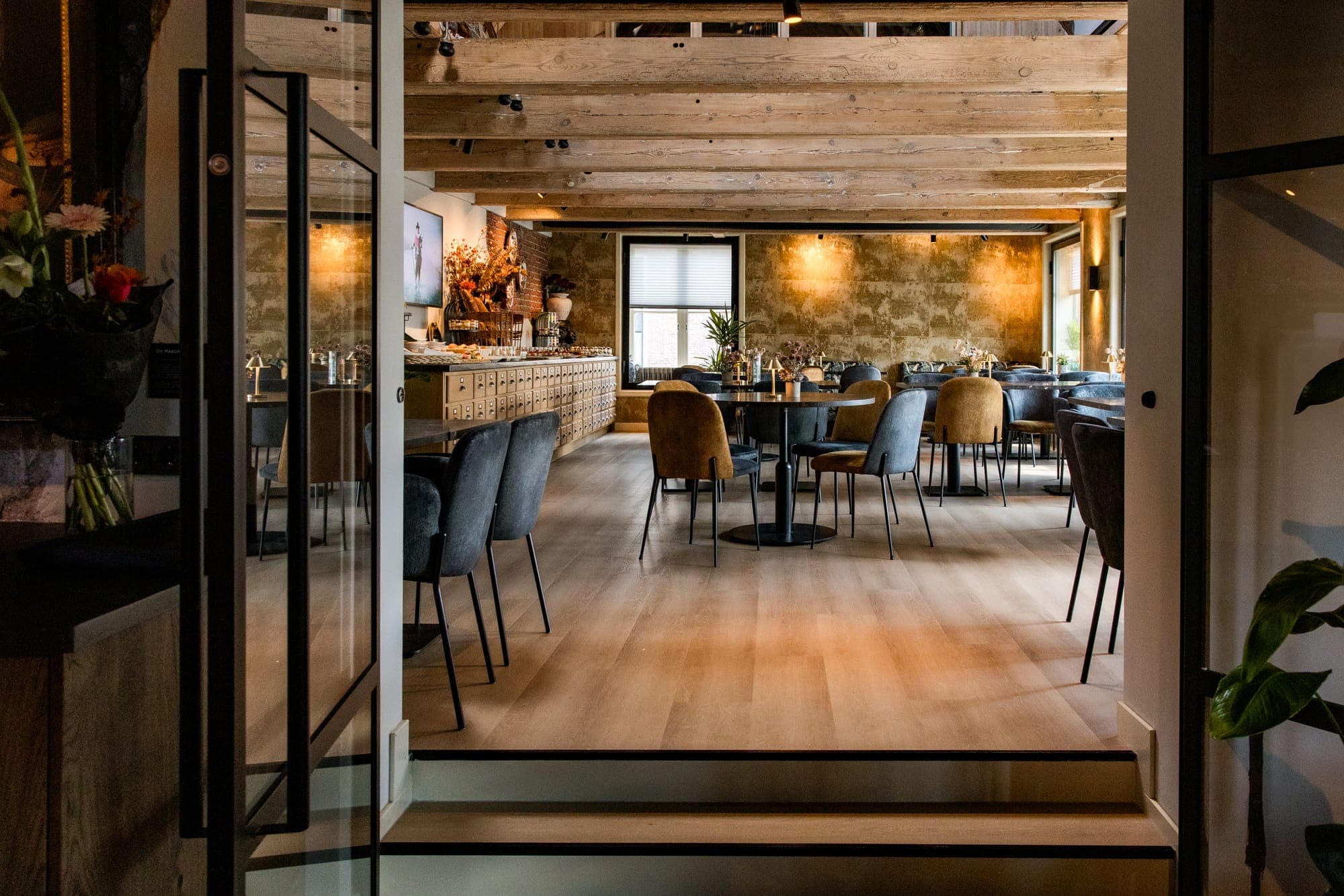 Vernieuwde zaal met houten plafond en glazen deuren bij De Haas