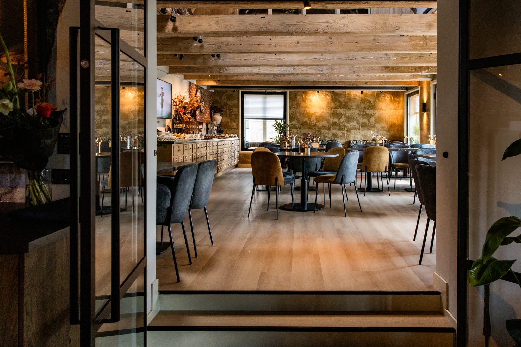 Vernieuwde zaal met houten plafond en glazen deuren bij De Haas