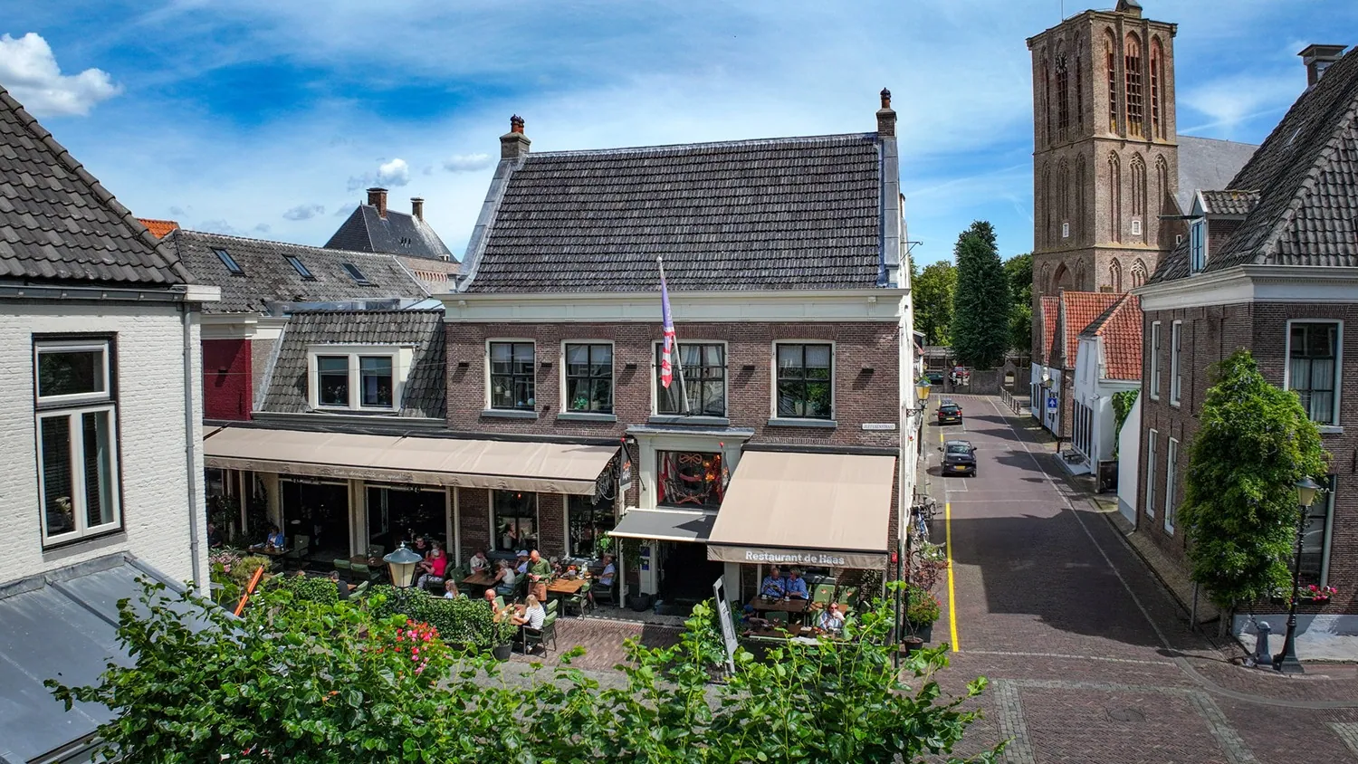 De Jufferenstraat in Elburg met het zonnige terras van De Haas en de Vischpoort aan het eind van de straat