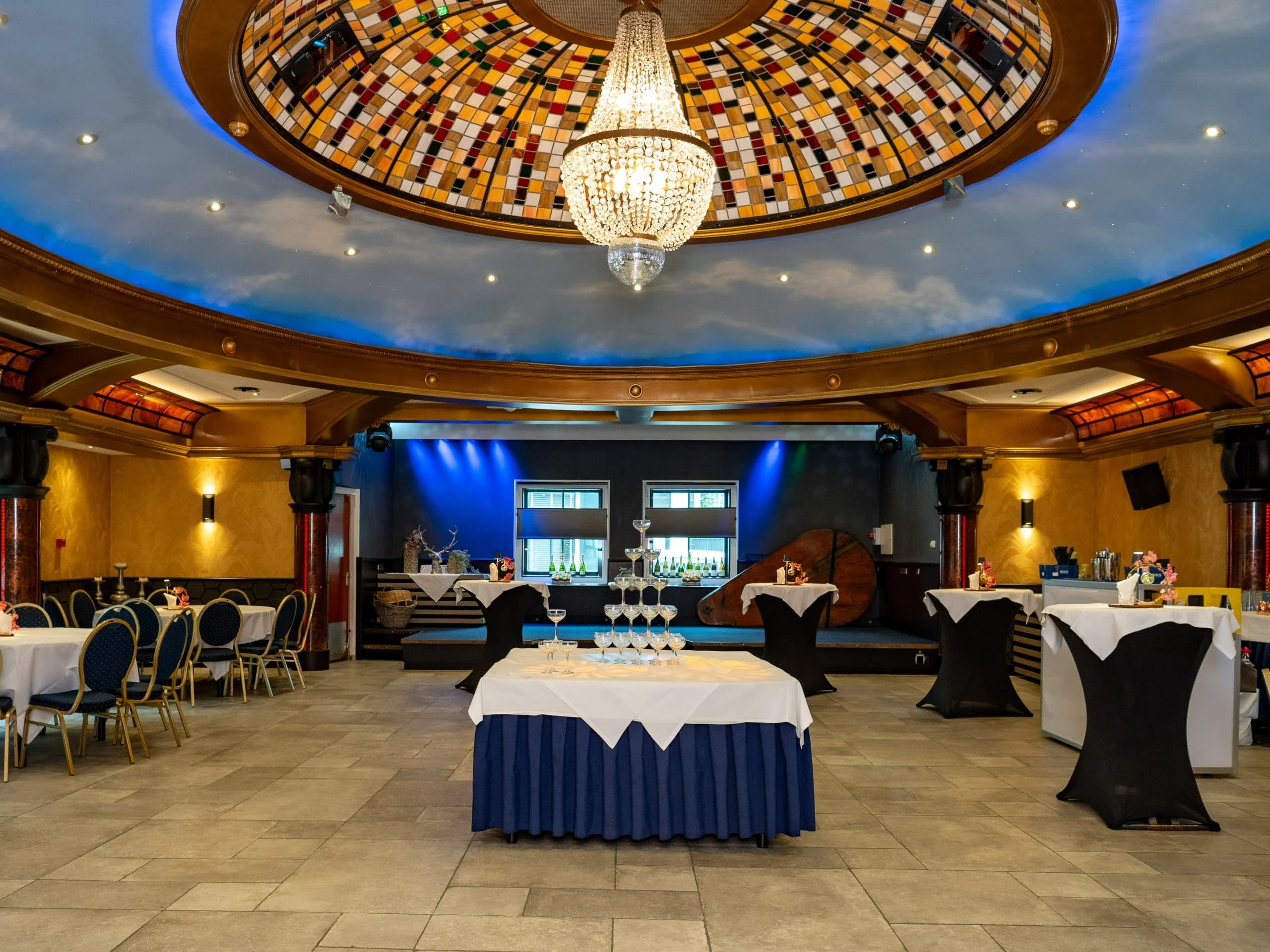 Sterrenzaal met glas-in-loodkoepel, kroonluchter, dansvloer en verlichte bar
